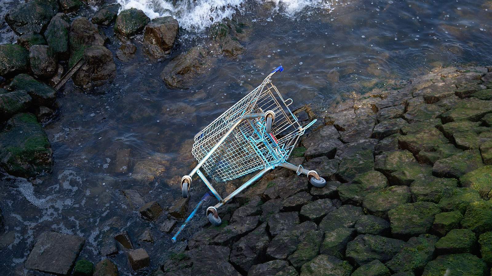A lone metal shopping cart standing in an empty parking lot at dusk under warm amber light